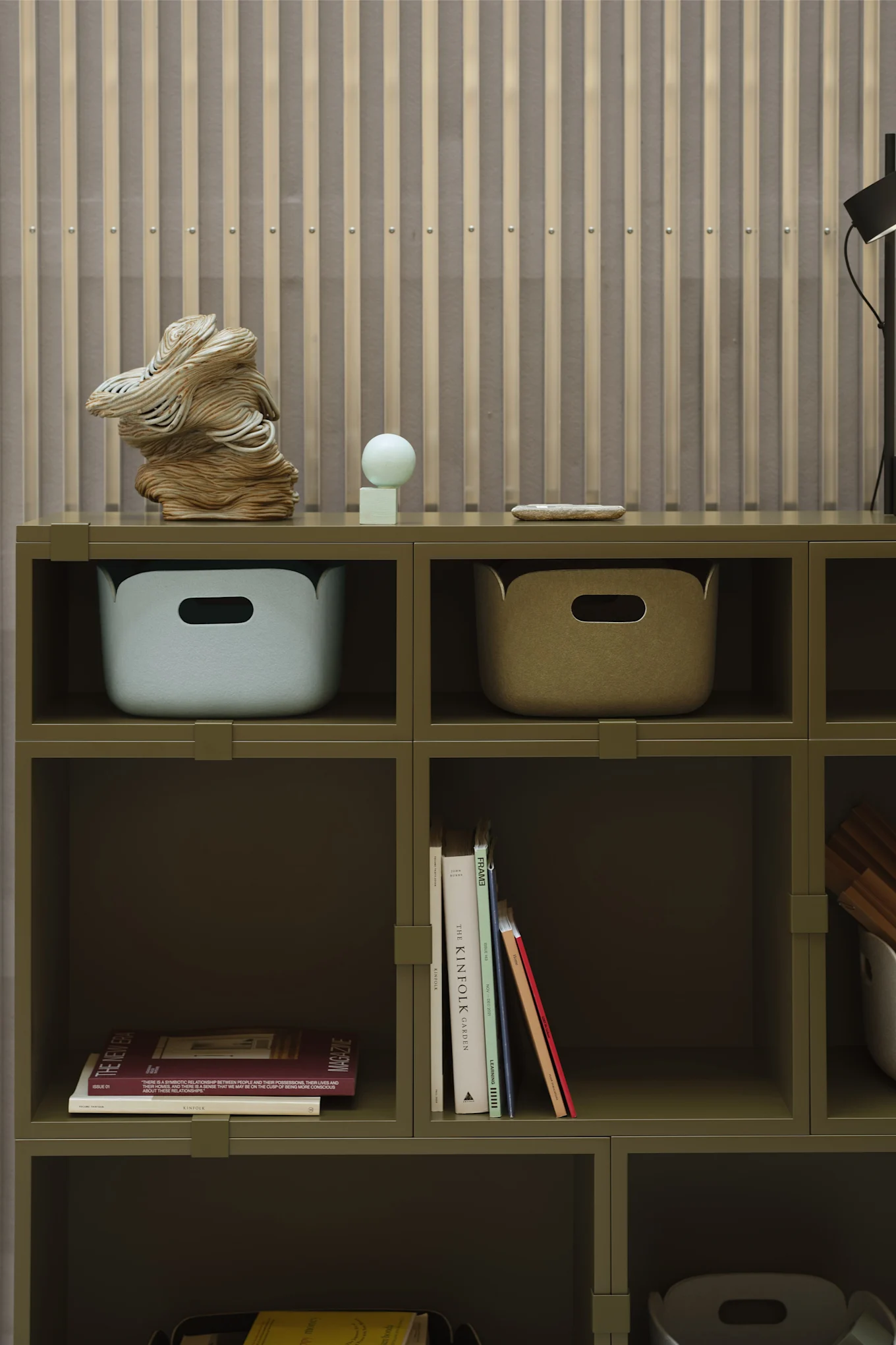 Une étagère verte avec des boîtes de rangement et des livres comme détails, en parfaite harmonie avec les tendances déco 2026.