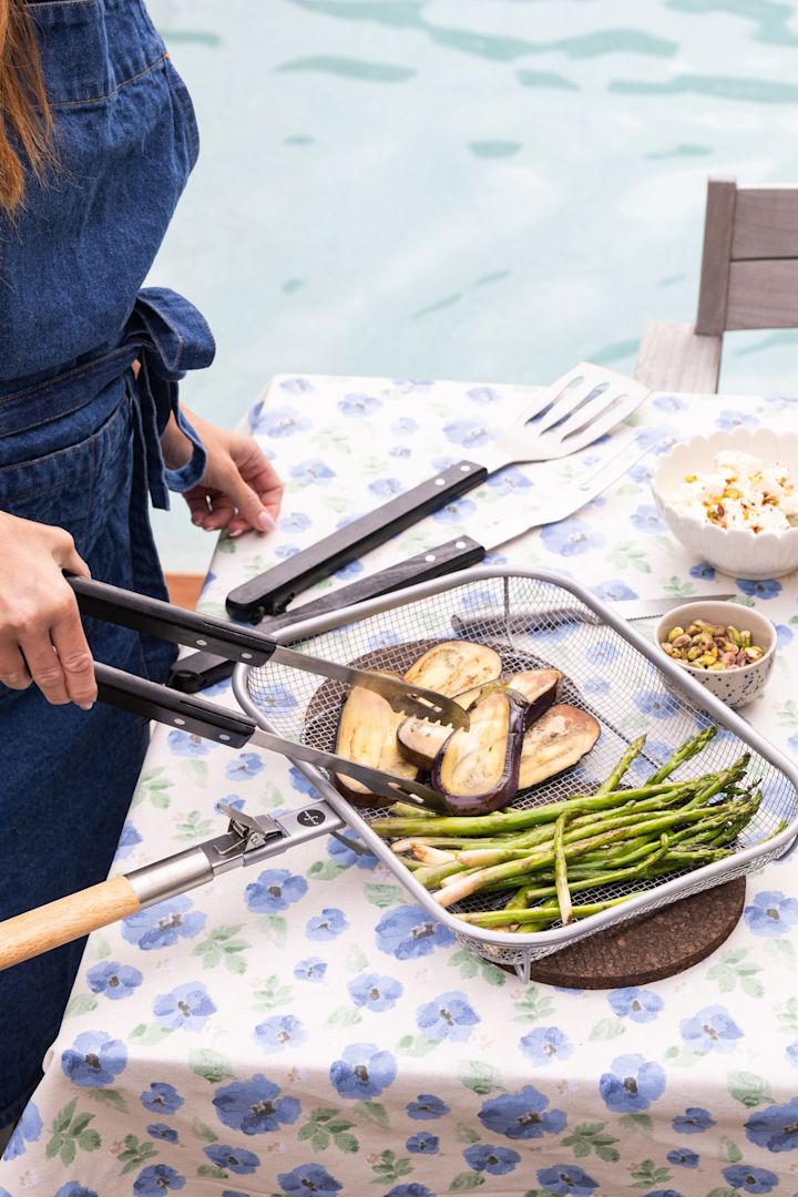 Ici, une femme retourne des aubergines et des asperges lors d'un barbecue d'été.
