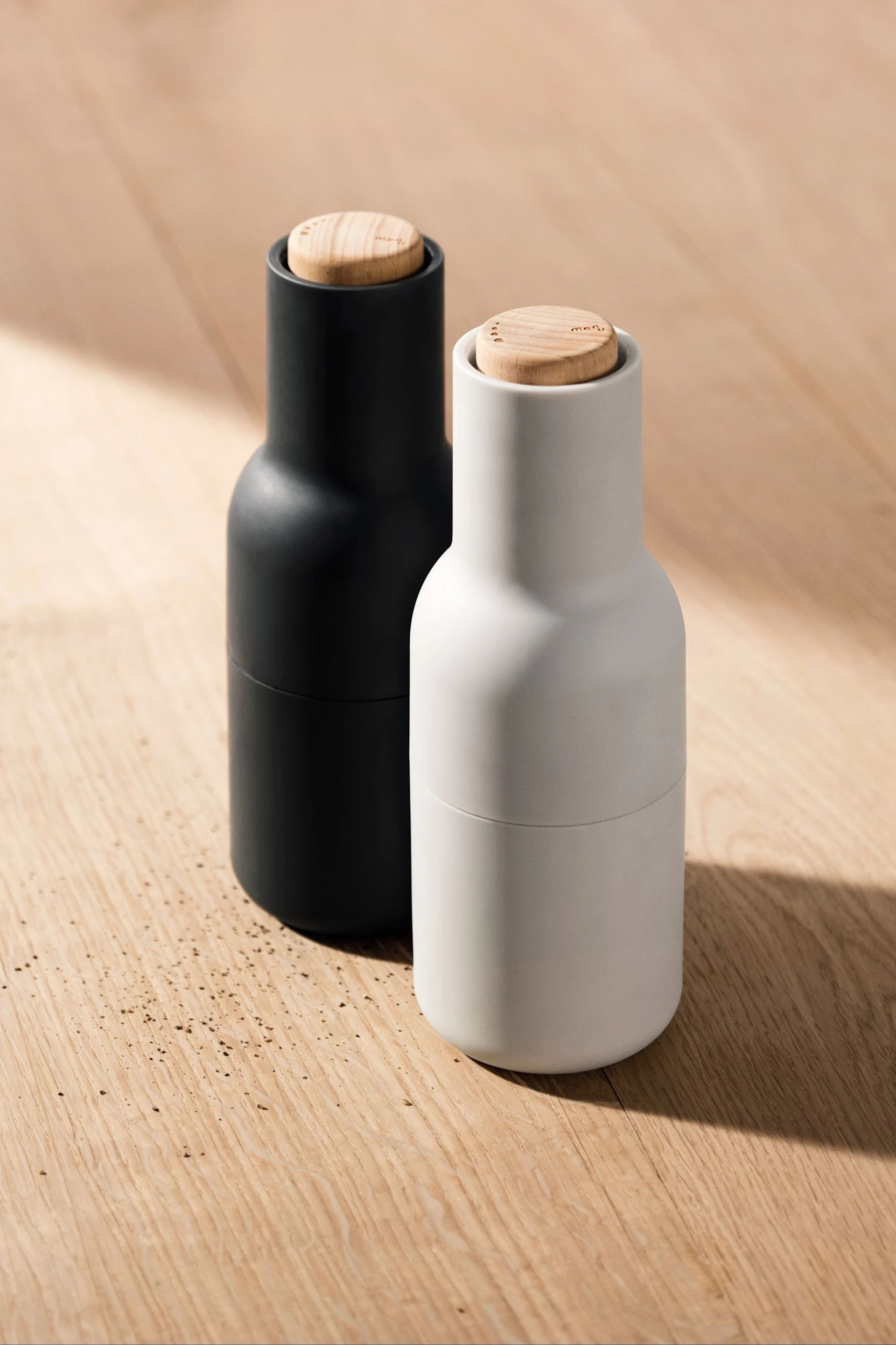 Vous voyez ici deux broyeurs à bouteilles d'Audo Copenhagen posés sur une table en bois.