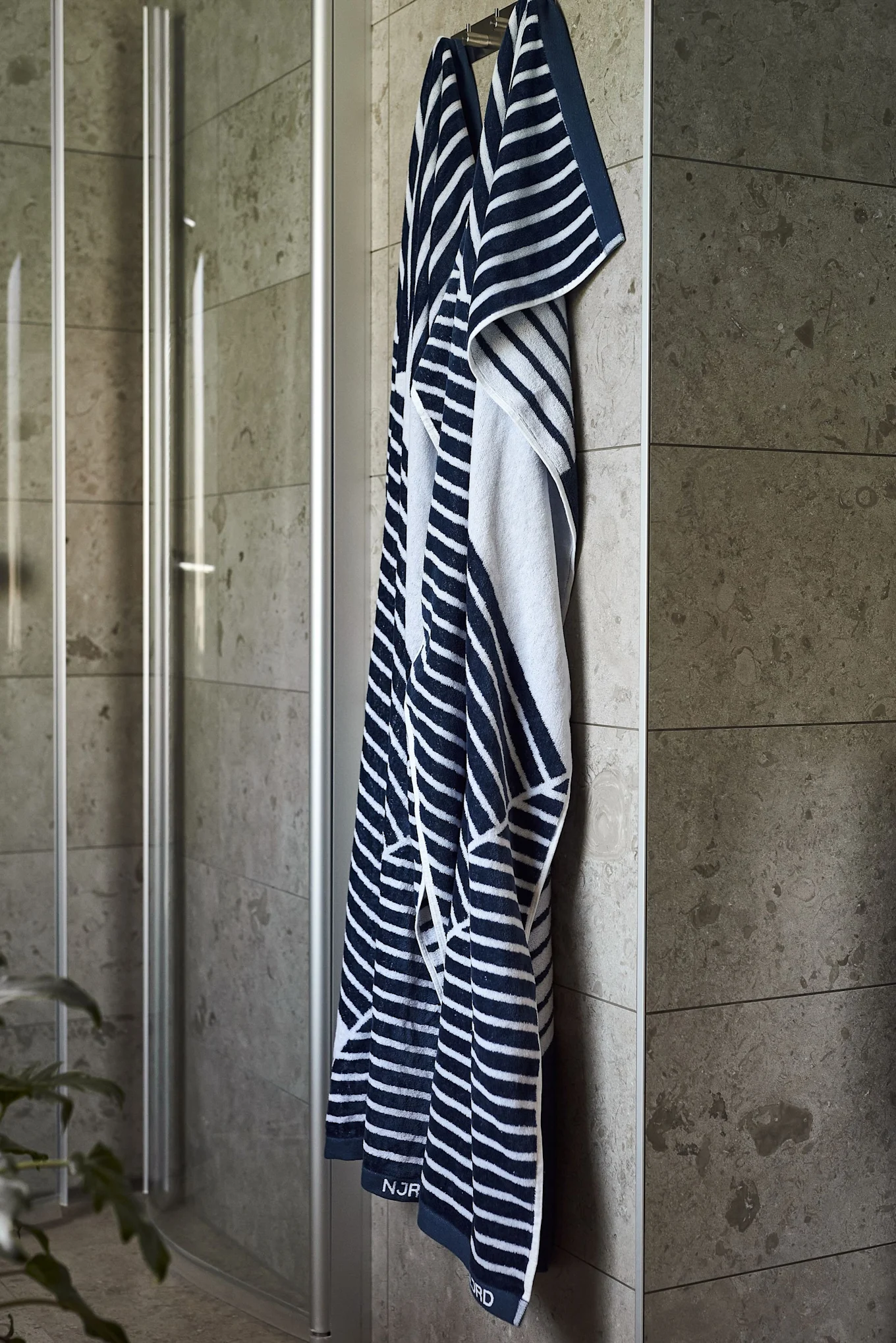 Offrez le drap de bain Stripes de NJRD pour la fête des pères aux amateurs de sauna, suspendu ici devant une douche.