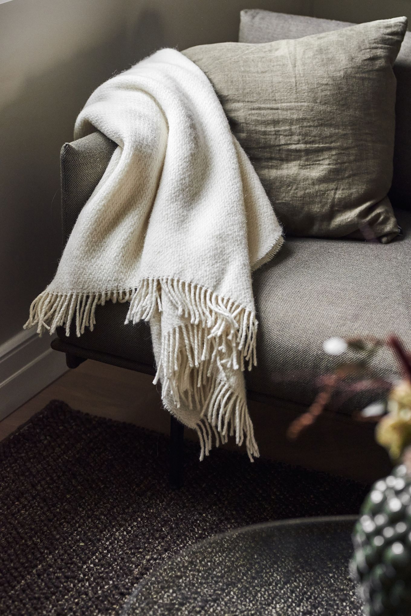 Une couverture douillette est un excellent cadeau pour la fête des mères. Ici, la couverture blanche Sandstone de Scandi Living est posée sur un canapé.