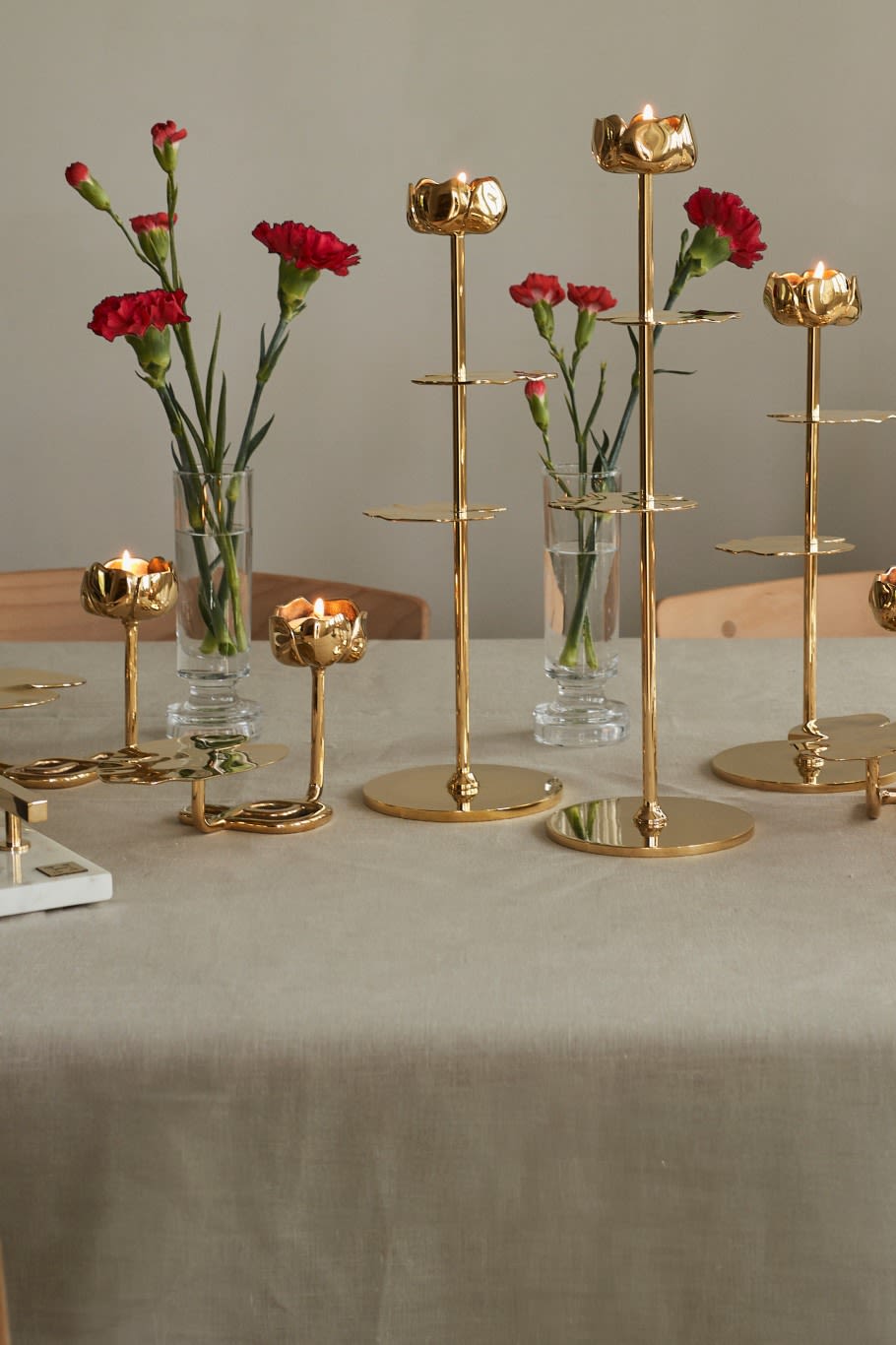 Offrez les bougeoirs de la collection Ninfea d'Hilke, présentés ici avec des fleurs rouges sur la table et caractérisés notamment par leur forme de nénuphar.