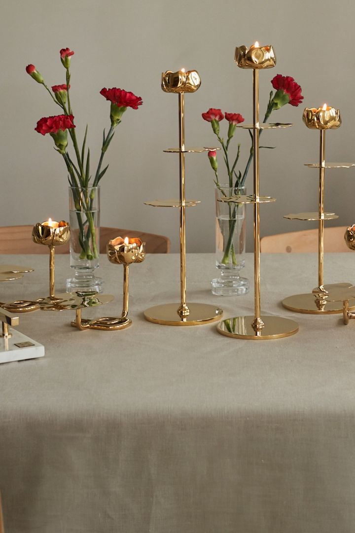 Offrez les bougeoirs de la collection Ninfea d'Hilke, présentés ici avec des fleurs rouges sur la table et caractérisés notamment par leur forme de nénuphar.