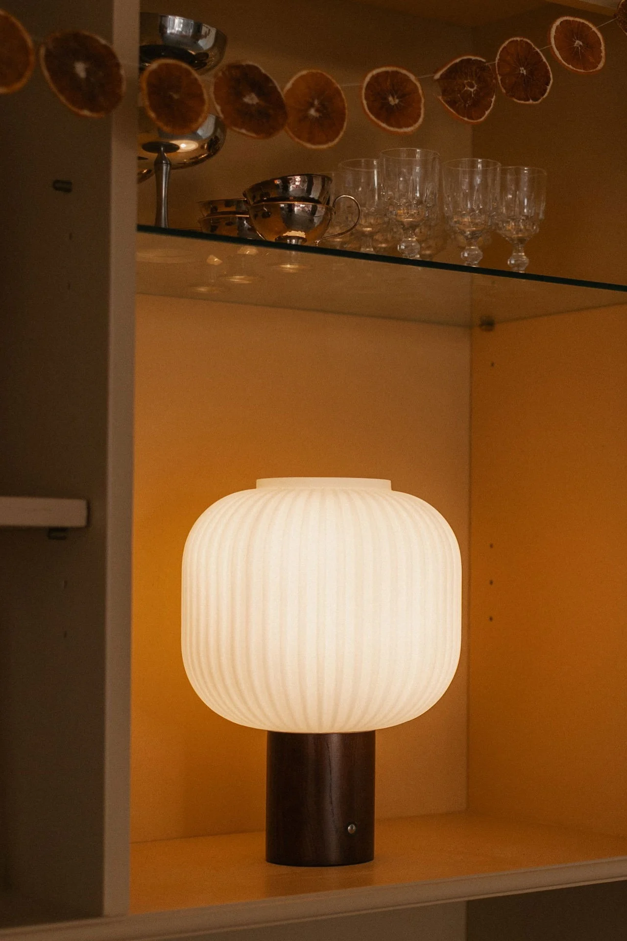 La lampe rechargeable Fair de Scandi Living est posée sur une étagère et éclaire la pièce.  