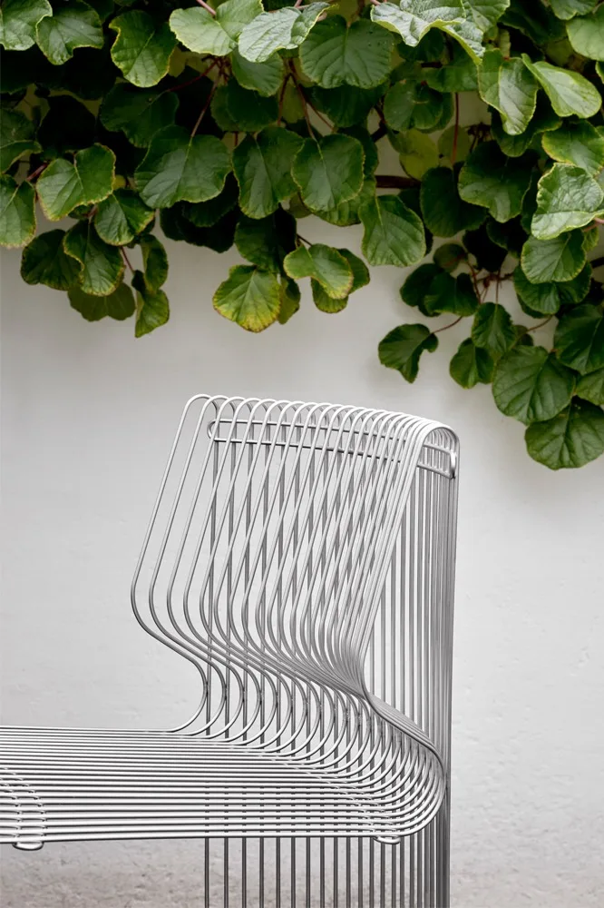 Une partie du canapé modulaire Panonova est exposée à l'extérieur, entourée de plantes grimpantes.