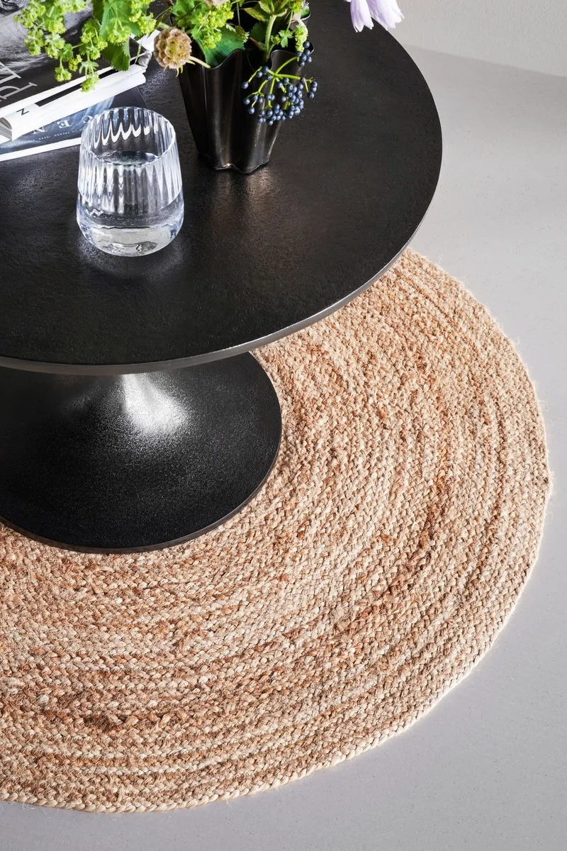 Le tapis rond en jute Rugy de House Doctor, qui convient parfaitement à une décoration bohème grâce à sa matière, est posé sous une table ronde noire.