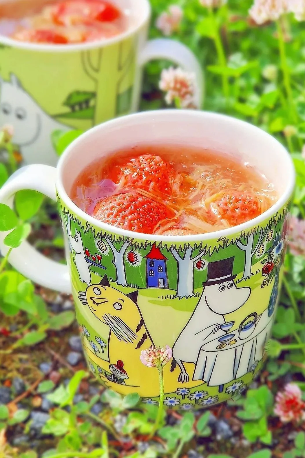 Le mug Moomin de l'été 2023, “Garden Party”, se trouve dans le jardin de @jasmiiniflower, rempli de framboises.