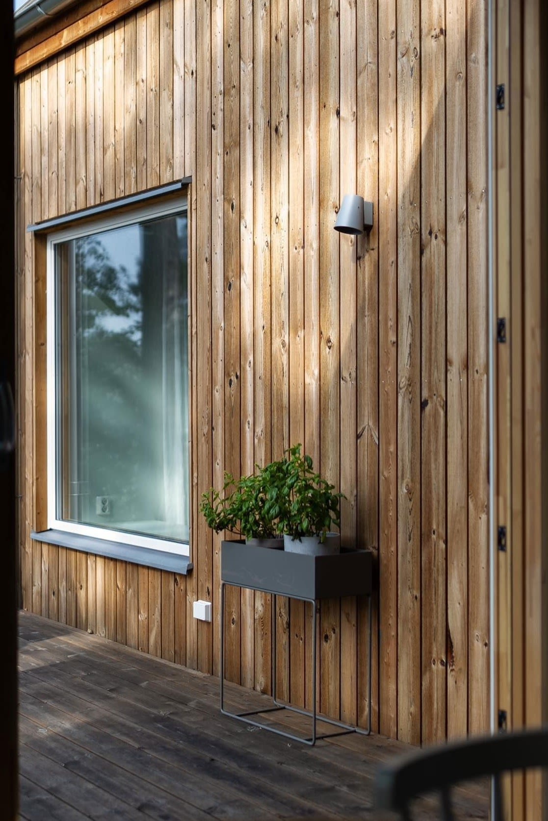 Ici, la jardinière en métal noir de Ferm Living se trouve sur la terrasse d'une maison Suédoise en bois.