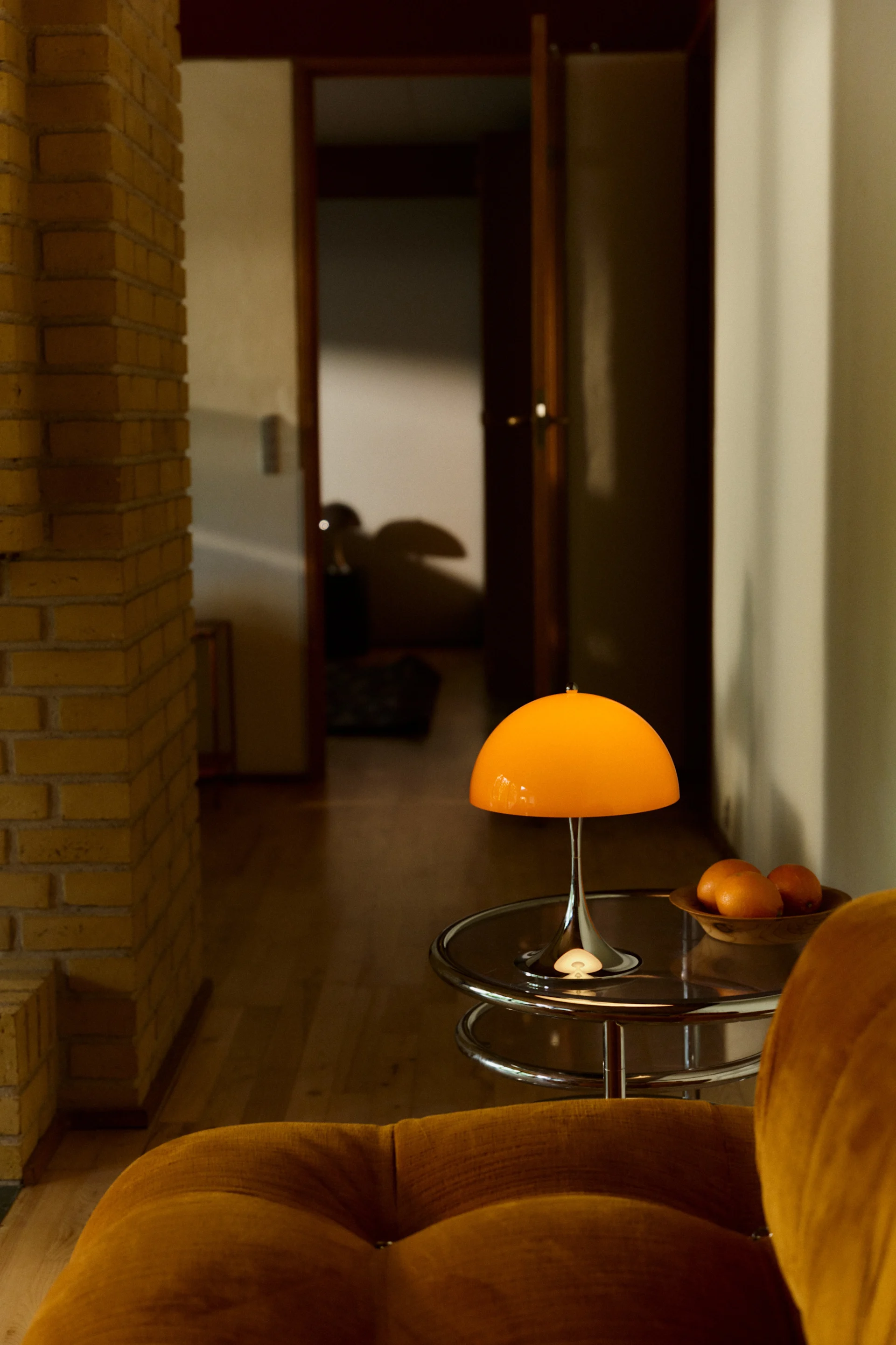 La lampe rechargeable Panthella 250 est posée sur une table d'appoint chromée et éclaire la pièce.