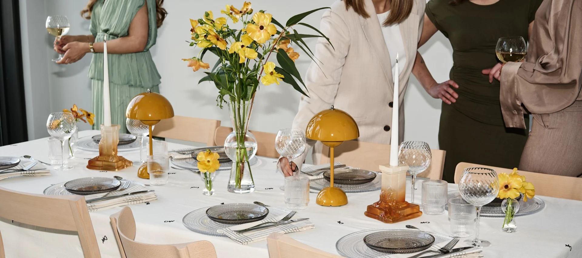 Comment organiser une fête avec une véritable ambiance festive : ici, vous voyez une table dressée avec des touches de jaune et des invités qui échangent autour de la table.