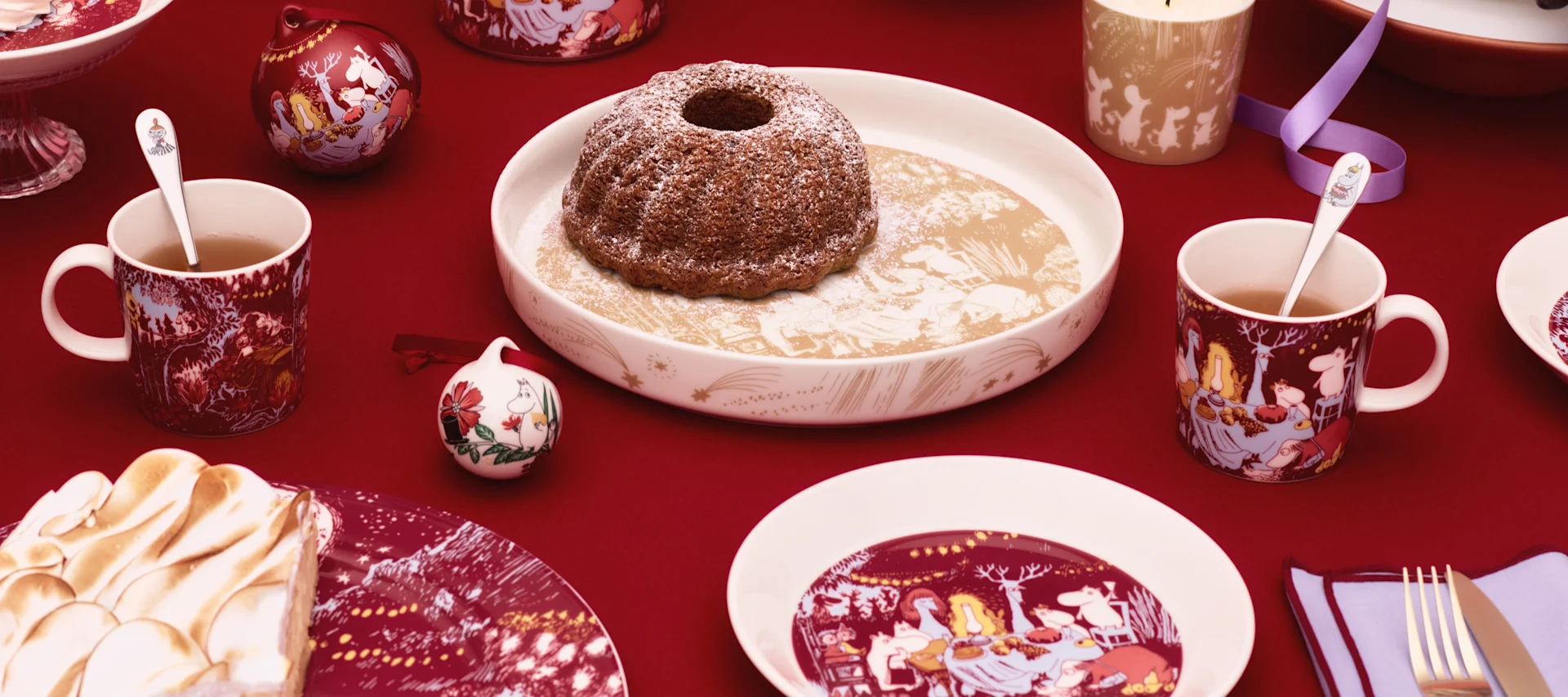 Diverses tasses Moomin de l'Arabie Moomin sont posées sur une table à l'extérieur, à côté d'un pot d'estampage.