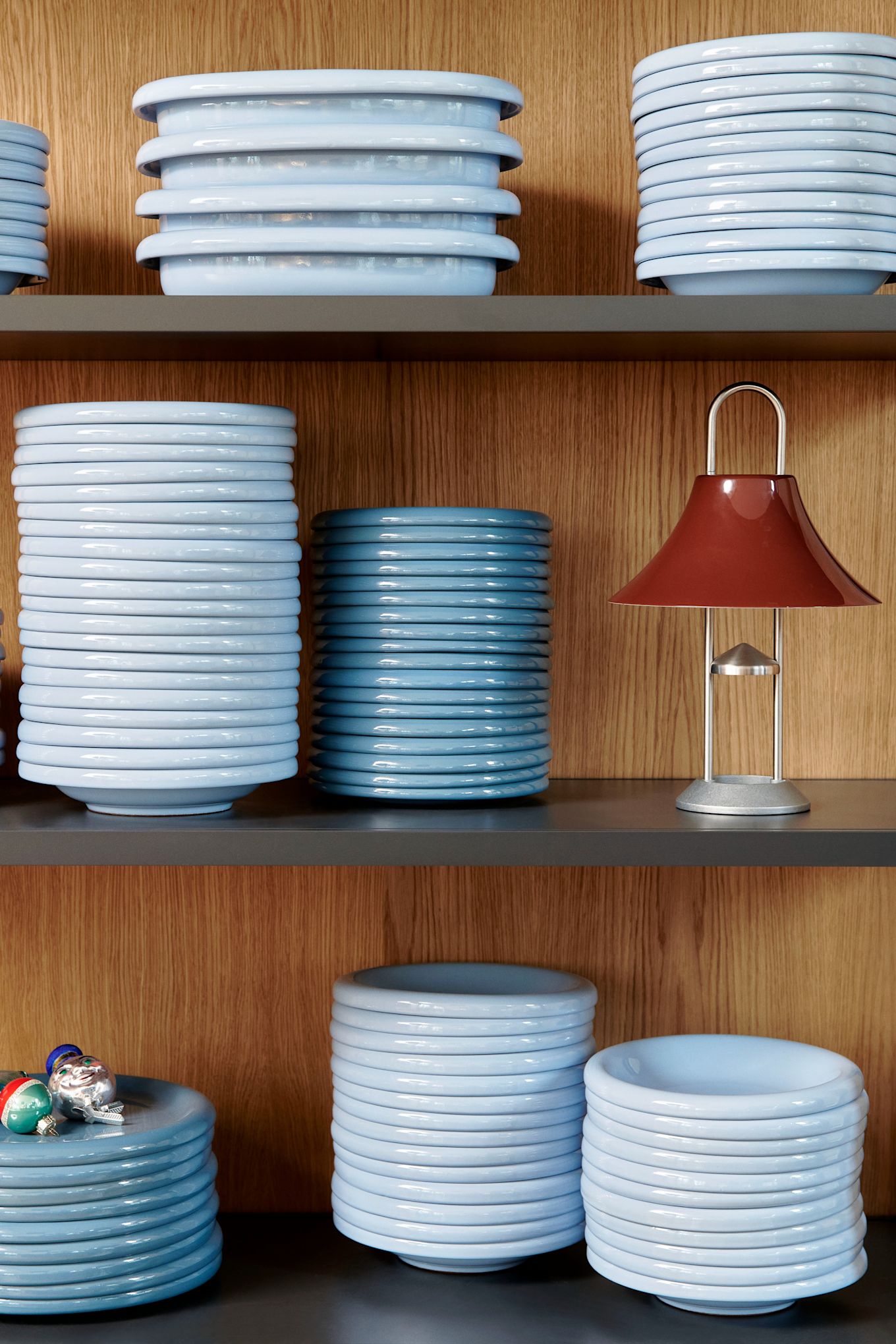 Le bleu ciel est une couleur importante dans les tendances des couleurs d'intérieur 2025. Ici, vous voyez une pile d'assiettes barro de Hay empilées dans une étagère en bois. 
