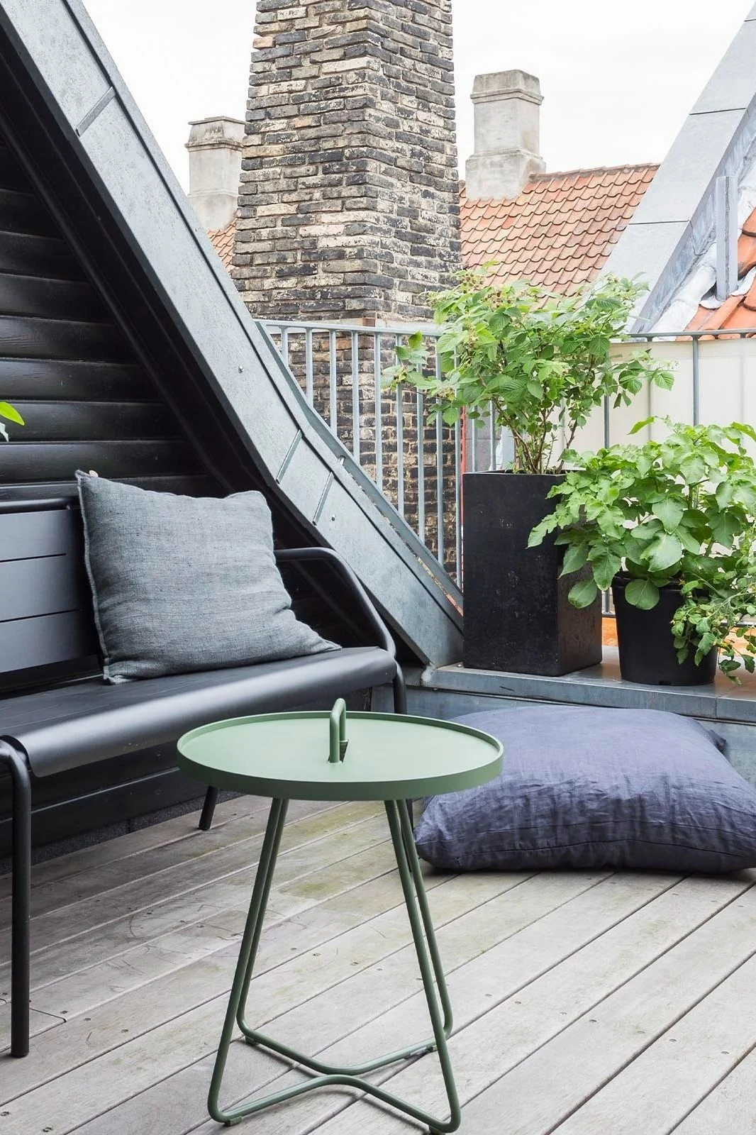 La table On the move de Cane-line, ici posée sur un balcon, séduit non seulement par sa couleur verte, mais aussi par sa multifonctionnalité et s'inscrit donc parfaitement dans les tendances 2025 en matière de mobilier de jardin.