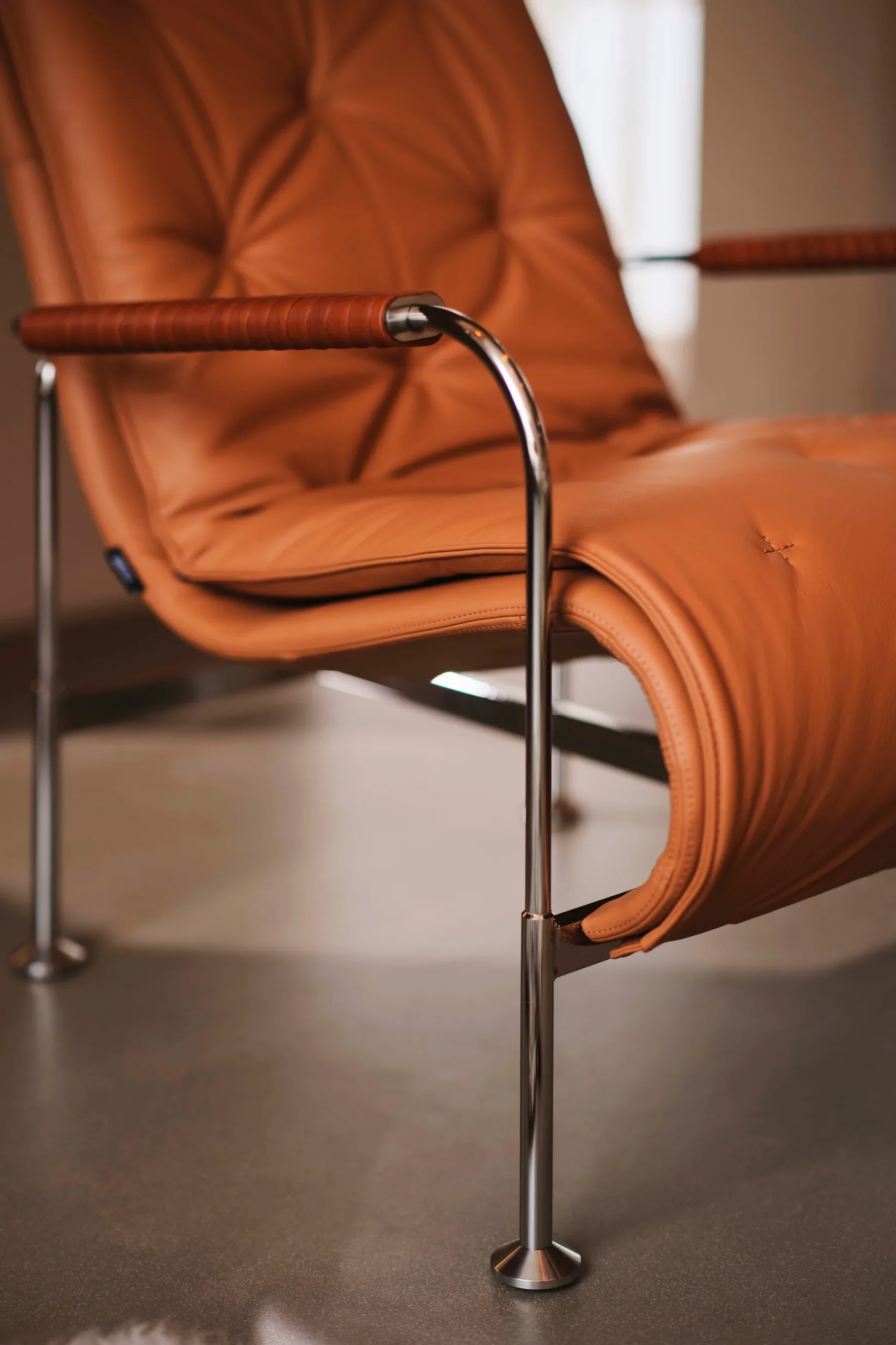 Fauteuil en cuir beige avec structure chromée et accoudoirs rembourrés.
