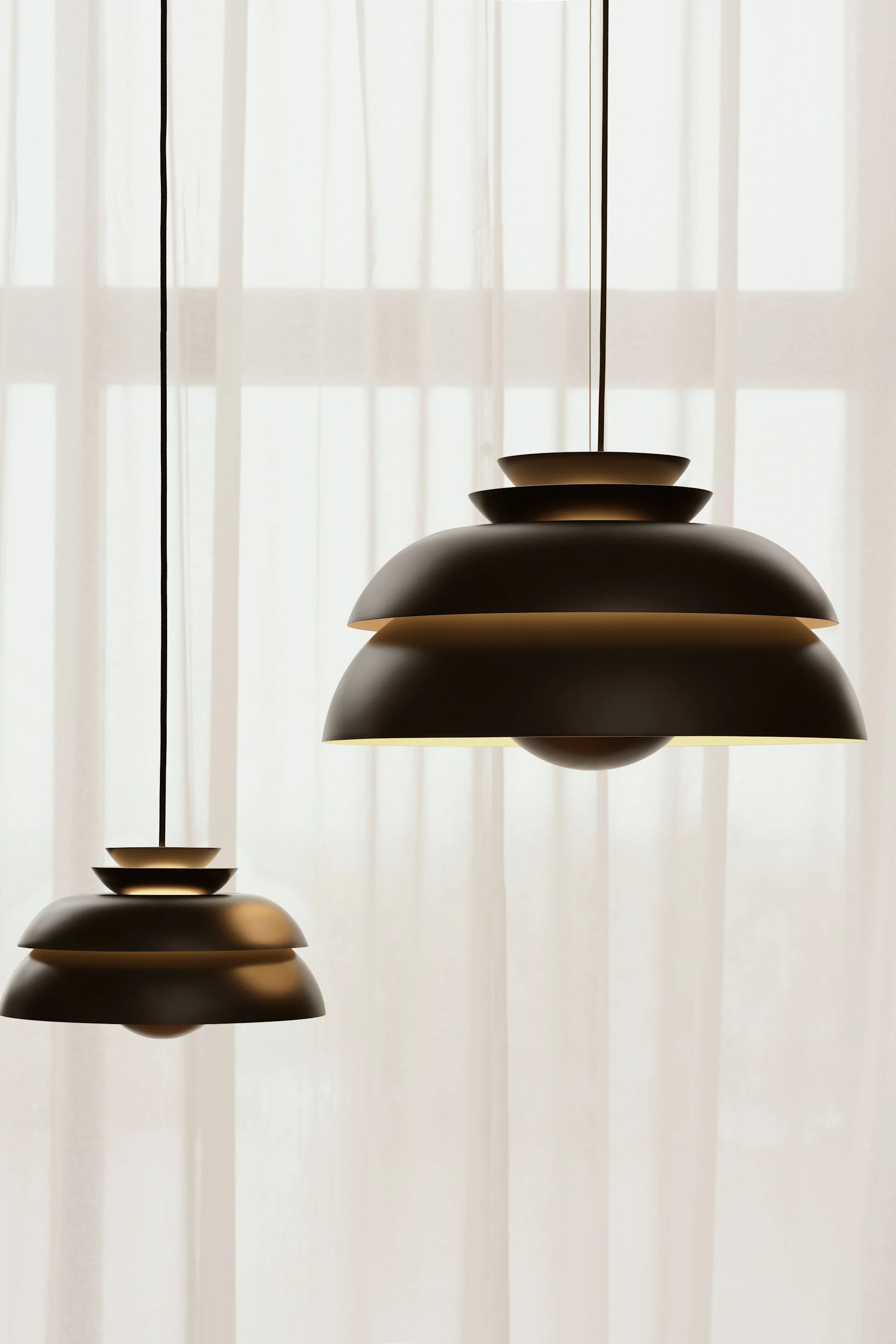 La suspension Concert noire de Fritz Hansen est suspendue devant une fenêtre avec des rideaux.