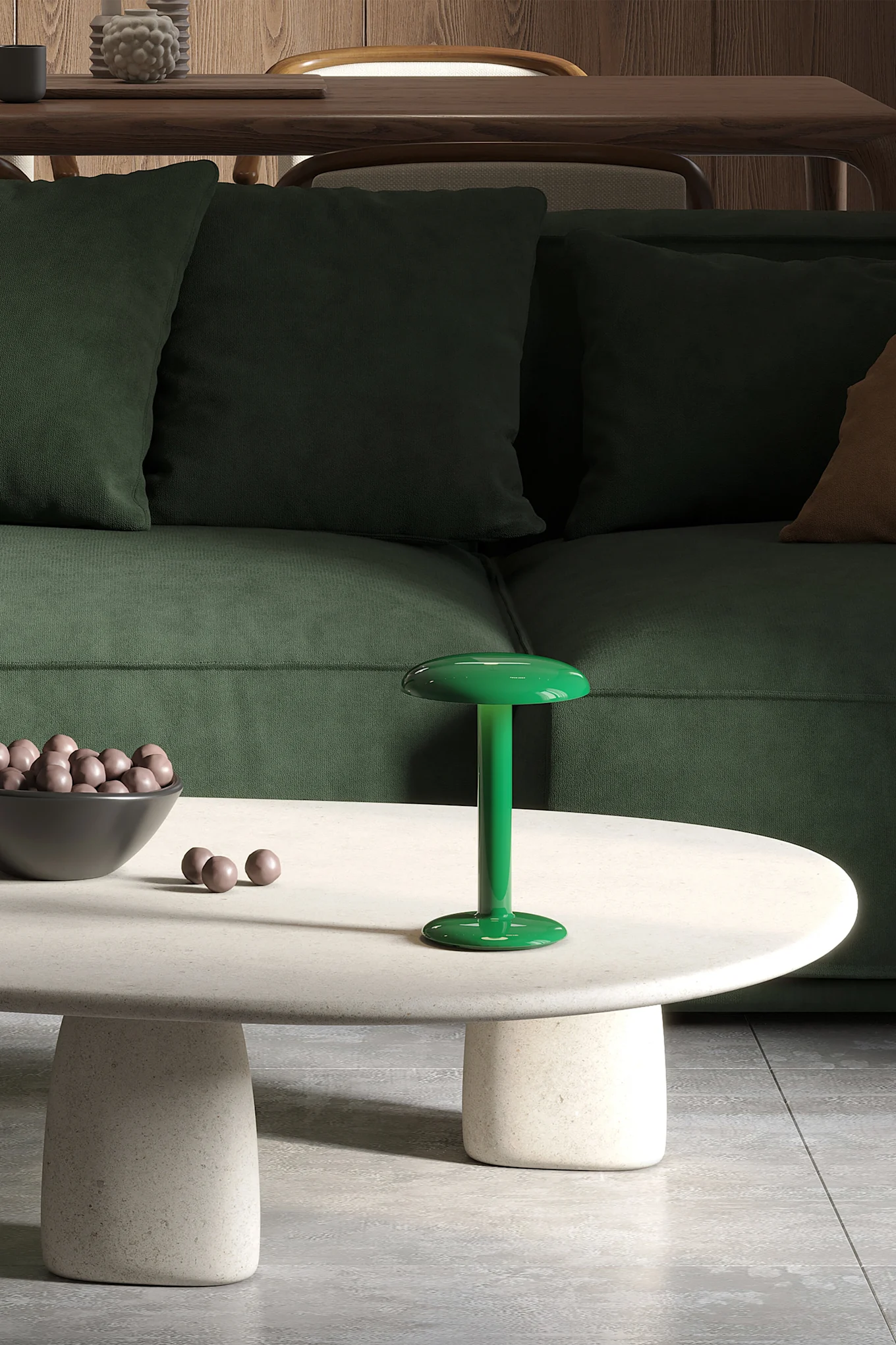 La lampe rechargeable verte Gustave Residential de Flos est posée sur une table basse blanche, avec un canapé vert en arrière-plan.