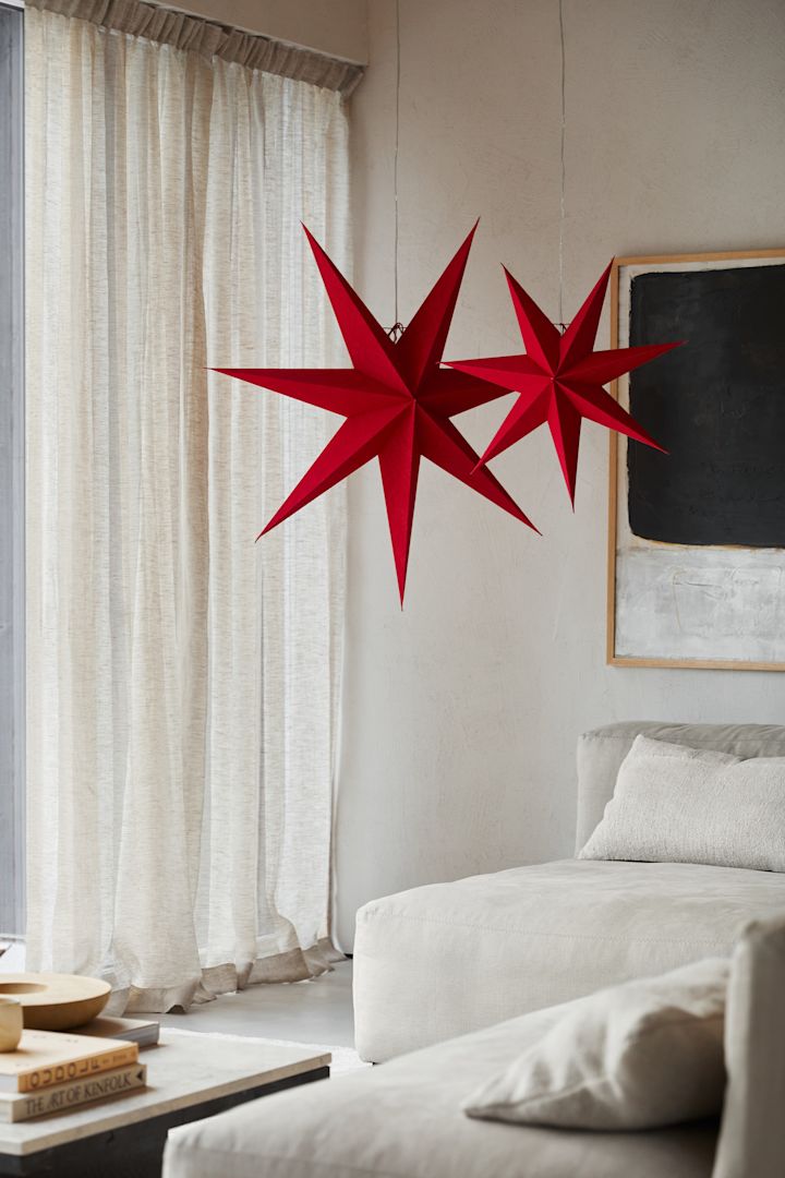 Deux étoiles en papier rouge de Watt & Veke suspendues ensemble dans un salon. 