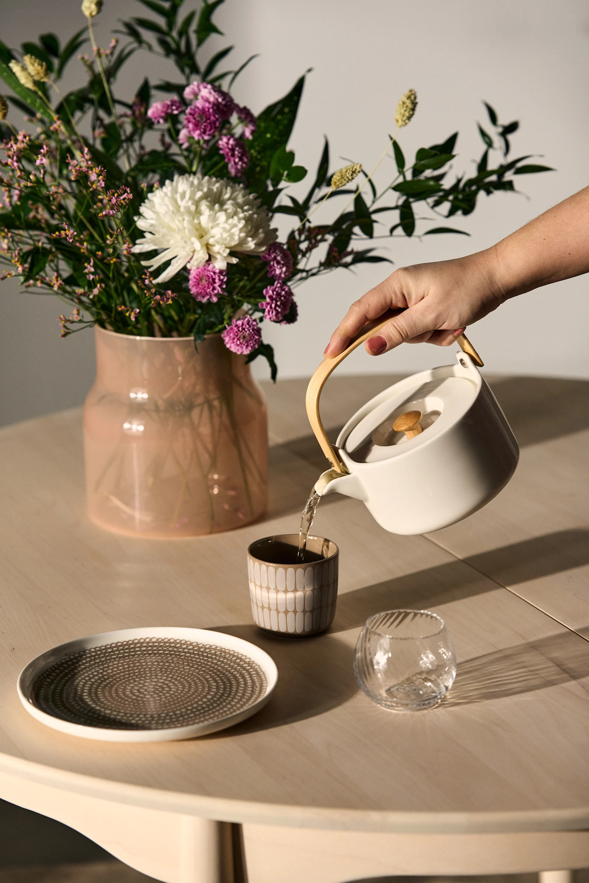 La Saint-Valentin invite à profiter pleinement des moments passés ensemble. Offrez une théière élégante, comme la Oiva de Marimekko, dont le contenu vient d'être versé dans une tasse sur une table dressée.