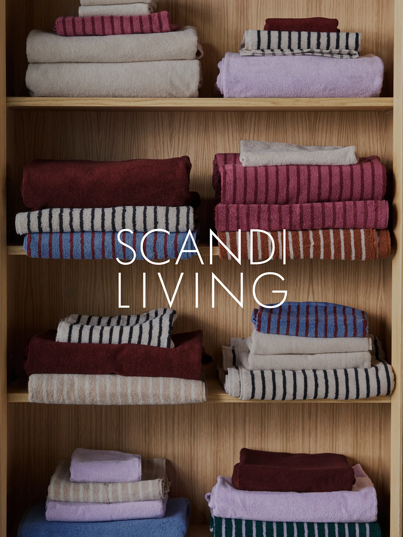 Texte SCANDI LIVING sur des serviettes empilées et pliées de différentes couleurs et motifs sur des étagères en bois.