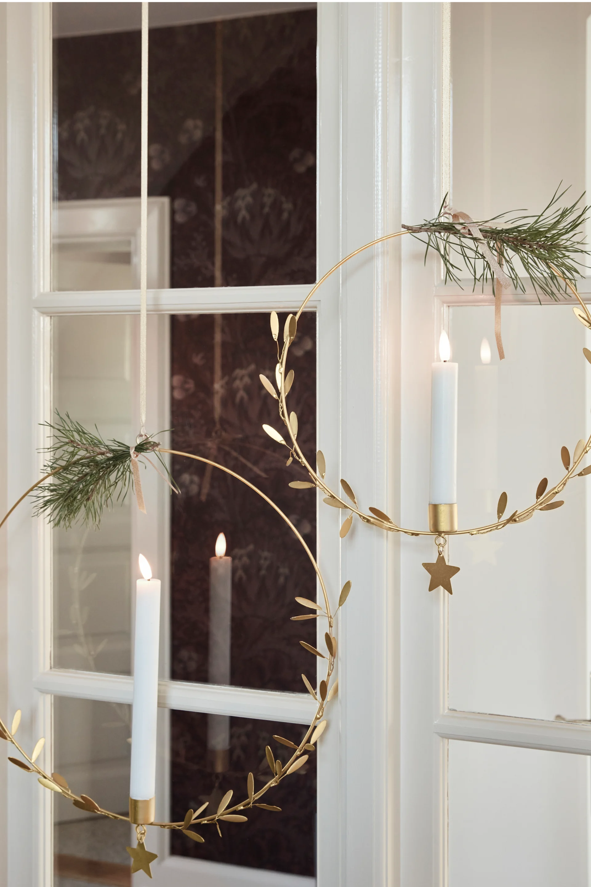 Décorez vos fenêtres pour Noël, par exemple avec les bougeoirs **Misten** de **House Doctor**, qui sont ici suspendus dans une fenêtre.