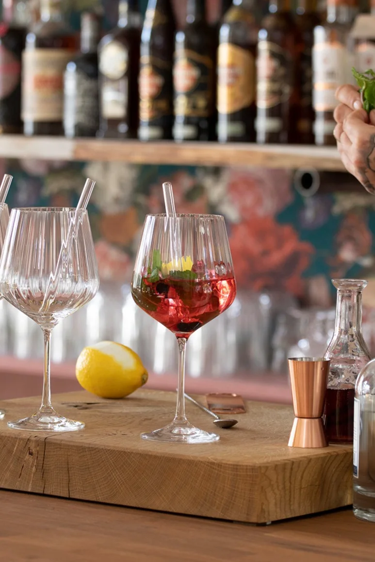 Un cocktail sans alcool servi dans un verre Nachtmann Feel Good G&T est posé sur une planche en bois devant un bar.